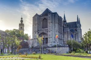 eine große Kathedrale mit Flaggen davor in der Unterkunft Appart Mons Station Center in Mons