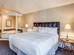 1 dormitorio con 1 cama blanca grande y 2 mesas en Leavenworth Village Inn, en Leavenworth