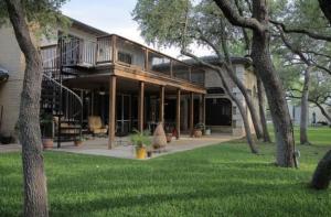 a large house with a porch with trees in the yard at Live Oaks Bed and Breakfast in Uvalde