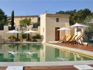 a pool with chairs and umbrellas next to a house at Le Mas de la Lause in Le Barroux