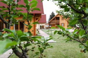 a building with a yard with trees in the foreground at Family Panzio es Apartman Hazak in Lipót +9 photos