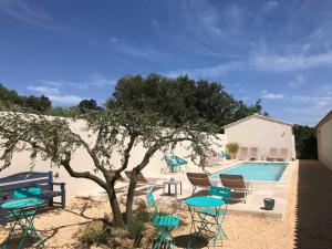 a pool with chairs and a table and a tree at Les Mazets et Spa D'Uzes in Arpaillargues-et-Aureillac