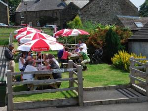 a group of people sitting at tables with umbrellas at The Miners Arms in Eyam