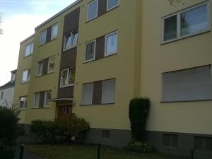 un bâtiment jaune avec des fenêtres à volets dans l'établissement Fewo Neukirchen mit Balkon, à Neukirchen-Vluyn