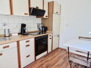 - une cuisine avec des placards blancs et un lave-vaisselle noir dans l'établissement Fewo Neukirchen mit Balkon, à Neukirchen-Vluyn