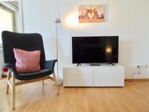 a living room with a chair and a flat screen tv at Fewo Neukirchen mit Balkon in Neukirchen-Vluyn