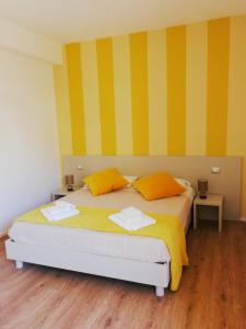 um quarto com uma cama com riscas amarelas e amarelas em HouseSandra Mare & Sole em Alghero