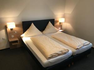 a bedroom with a bed with two pillows and two lamps at Motel Herbold in Knüllwald