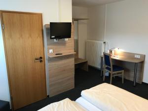 a hotel room with a bed and a desk with a television at Motel Herbold in Knüllwald