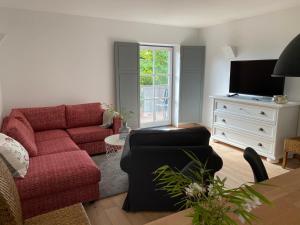 uma sala de estar com um sofá vermelho e uma televisão em Gemütliches Domizil über den Dächern von Jena em Jena