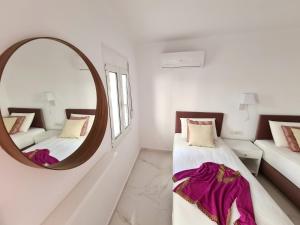 une chambre blanche avec deux lits et un miroir dans l'établissement Monte Smith City Home, à Rhodes