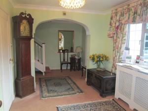 Sala de estar con reloj de abuelo y mesa en Newmans Hall Bed & Breakfast, en Little Waldingfield