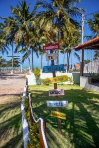 a street sign in front of a beach with palm trees at Parque dos Coqueiros- Bangalos e Suites in Maragogi