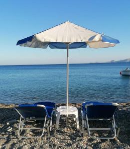 two chairs and an umbrella on the beach at FantaSea Apartments in Haraki