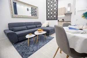 uma sala de estar com um sofá azul e uma mesa em Theatre Square Apartments em Novi Sad