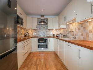 a kitchen with white cabinets and a wooden floor at The Bolt Hole in Torpoint