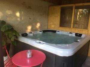 bañera de hidromasaje en una habitación con mesa roja en Le Clos Elisa, en Saint Laurent Nouan