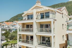 un edificio de apartamentos con balcones y una montaña en el fondo en Apartments Villa Swissmonte, en Herceg-Novi