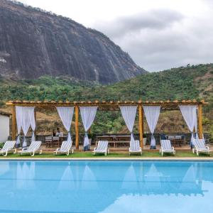 a wedding venue with a pool and chairs and a mountain at Hotel Fazenda Santa Helena in Simão Pereira