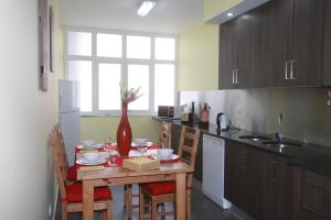 a kitchen with a wooden table with chairs and a vase at A Casa do Centro in Peniche