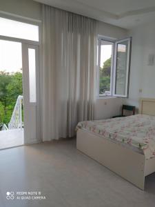 a bedroom with a bed and windows and a balcony at Emzari's Apartment in Kobuleti