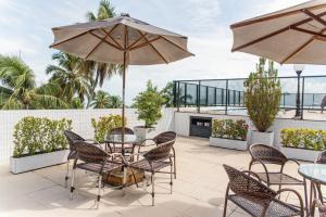 un patio con mesas, sillas y una sombrilla en Nobile Inn Cabo Branco, en João Pessoa