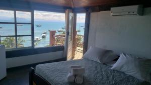 a bedroom with a bed with a view of the ocean at Bardot Apartamentos in Búzios