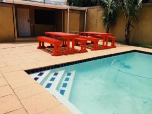 a group of red picnic tables and a swimming pool at Bentley Lodge & Lifestyle in Durban
