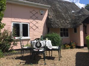 a table and chairs in front of a pink house at Lou's B&B in Theale