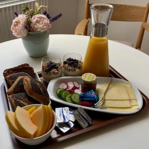 a tray of food with bread and orange juice on a table at Birgittes B&B i Jelling in Jelling