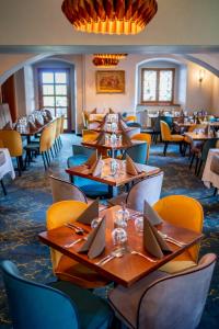 a restaurant with wooden tables and yellow chairs at Chateau Loucen Garden Retreat in Loučeň