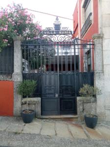 a black gate with potted plants in front of a building at Hotel Villa Maria in Fuentes de Béjar