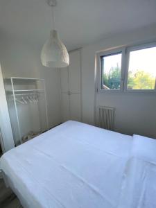 een witte slaapkamer met een wit bed en een raam bij Welcome Traveller APPARTAMENTO CASETTO in Bardolino