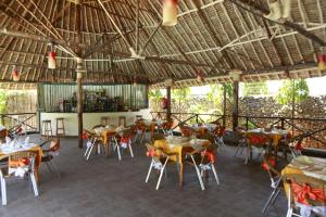 a restaurant with tables and chairs and a roof at Jacyjoka Apartments Nyali in Mombasa