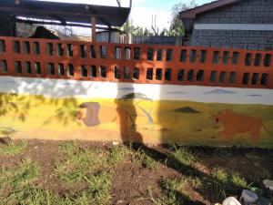 uma cerca com uma pintura de animais nela em Achill Houses em Thika