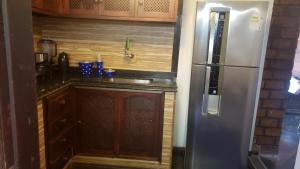 uma cozinha com um frigorífico de aço inoxidável e armários de madeira em Bardot Apartamentos em Búzios