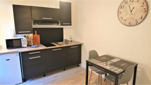 une cuisine avec une table et une horloge murale dans l'établissement Appartement T2 "Le Cocoön" rez-de-jardin au calme, à Vitré