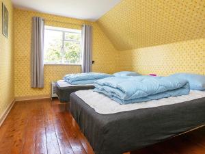 three beds in a room with yellow walls and a window at Holiday home Varde II in Varde