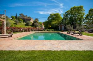 een zwembad in een tuin met twee banken bij Mas Vermell in Fontanilles