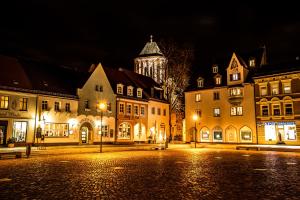 a city at night with a clock tower in the background at Markt 15 Gästehaus-Senftenberg in Senftenberg