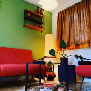 a living room with a red couch and green walls at Retro-huisje GoedFout in Olst