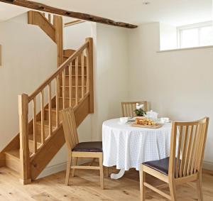 a dining room with a table with chairs and a staircase at Manor Farm Courtyard Cottages in Hampstead Norris