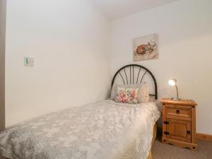 a bedroom with a bed and a wooden nightstand at The Old Goat Barn at Trout Cottage in Somerton