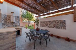 a patio with a table and chairs and a kitchen at Uliveto' s Apartment in Elmas