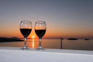 two glasses of wine sitting on a ledge with the sunset at Vesleme in Pachaina