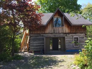 um chalé de madeira com um alpendre e uma porta em Merrickville Guest Suites em Merrickville