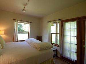 a bedroom with a white bed and two windows at Nettles Farm in Lummi Island
