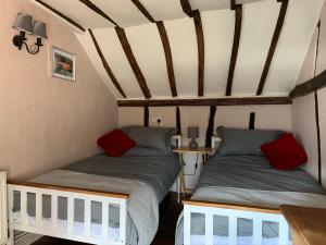 Duas camas num pequeno quarto com tectos em madeira em Myrtle cottage em Dickleburgh