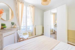 Habitación blanca con cama y espejo en MM Suites Reims Centre Terasse en Reims