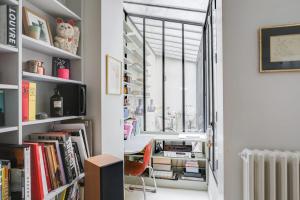een kamer met boekenplanken, een bureau en een raam bij Sumptuous house with patio in Parijs